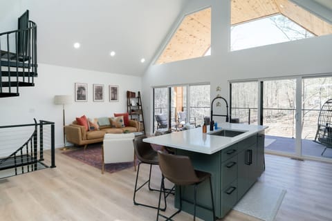 Bask in natural light and pond views from this stylish open-concept living area—featuring a fully equipped kitchen, cozy seating, and direct access to the outdoor deck.