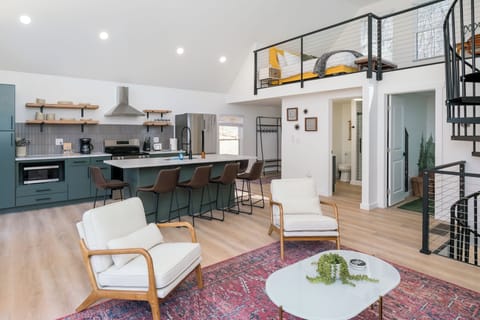 Bask in natural light and pond views from this stylish open-concept living area—featuring a fully equipped kitchen, cozy seating, and direct access to the outdoor deck.