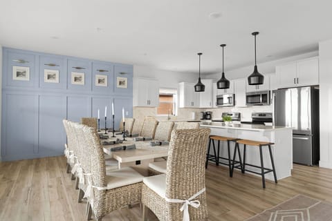 - Gather the whole group around the long dining table with comfy woven chairs and soft lighting
- Sleek black pendants and bar stools add modern flair to the white coastal kitchen
- Perfect for slow breakfasts, shared dinners, and late night snacks