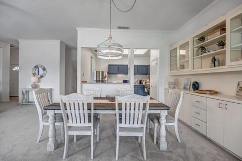 - Light and airy dining area with open kitchen pass through for easy mealtime flow
- Built in glass cabinets display charming decor and offer extra storage
- Crisp white palette and pendant lighting give the space a fresh, coastal cottage feel