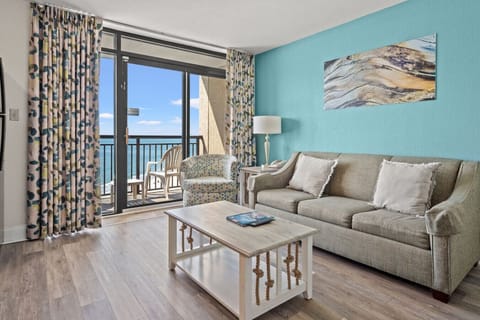 Step into this luxurious living room with oceanfront views, full-sized couch, queen-sized sleeper sofa, smart tv, and full kitchen