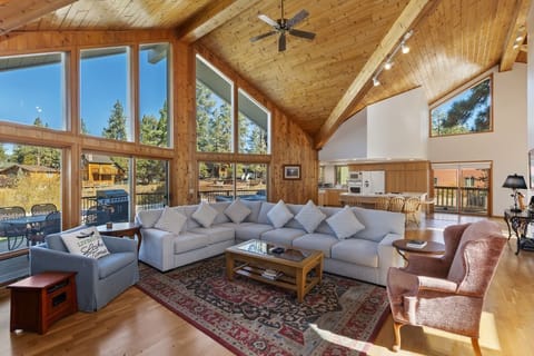 "Cozy up by the stone fireplace and enjoy stunning views through the large windows in this charming wooden living room."