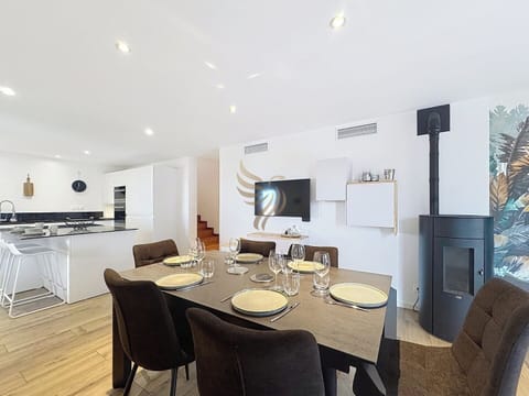 La table dans la salle à manger moderne offre un cadre parfait pour les repas en famille. Profitez de la chaleur du poêle tout en partageant des moments chaleureux dans cet espace lumineux et élégant.