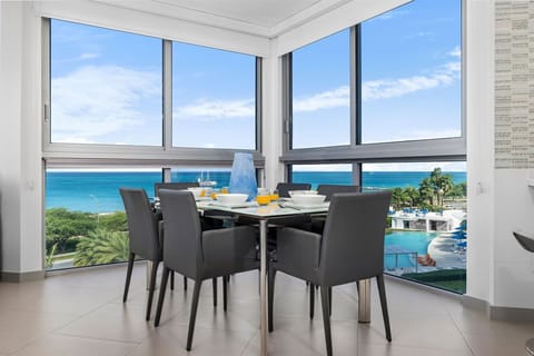 Enjoy breakfast or dinner at your dining table with stunning ocean views and a sparkling pool just below—your beachfront escape awaits right outside these floor-to-ceiling windows.