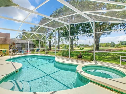 Screened-in private pool and hot tub with golf course views, outdoor seating, and plenty of sunshine for a perfect Florida retreat.