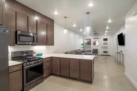 Open-concept design featuring a fully equipped kitchen with a gas range, pendant lighting, and seamless flow into the spacious living room.