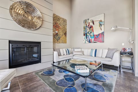 Welcome to your cozy retreat!  This stunning living room features a custom Italian-made couch, high ceilings, artistic decor, and a charming electric fireplace -perfect for unwinding after a fun day. Experience comfort & creativity in every corner! ️