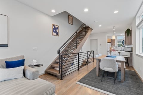 A modern, open-concept living space with a sleek staircase, cozy seating, and a stylish dining area.