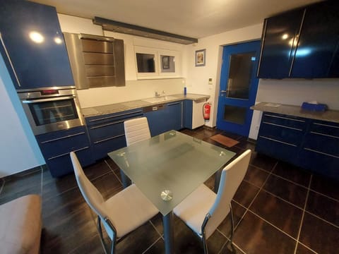 Kitchen with oven, ceramic plate, microwave and fridge.