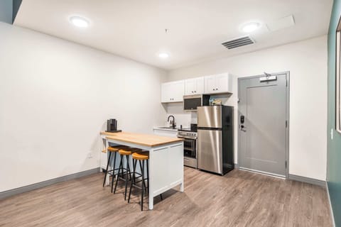 Cook and dine in style with a full kitchen featuring stainless steel appliances, a spacious island, and bar stools  —  perfect for meals and gatherings