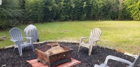 Fire pit in huge yard surrounded by bamboo.