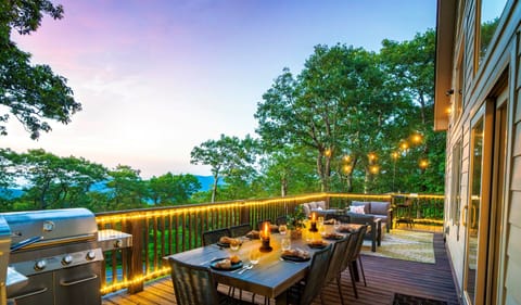 Twilight on the deck — mountains fading in the distance, wine glasses catching the glow of string lights, dinner sizzling on the grill. This is what gathering should feel like
