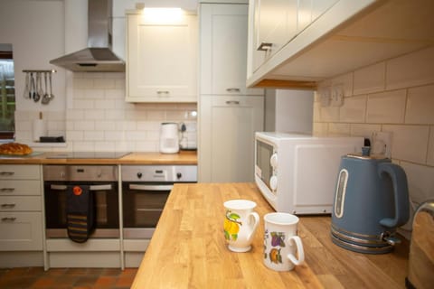 Modern kitchen with wooden worktop, microwave, kettle and two mugs
