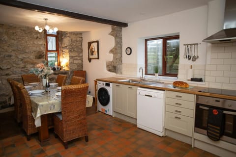 Rustic kitchen with stone walls, dining table and wicker chairs