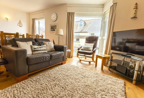 Lounge area with leather sofa, armchair, floor lamp and TV on stand