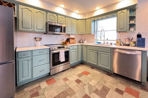 Spacious kitchen with charming green cabinets and a fully equipped setup for home-cooked meals.