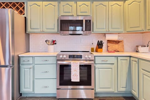 A charming kitchen with pastel cabinets, stainless steel appliances, and all the essentials for home-cooked meals.