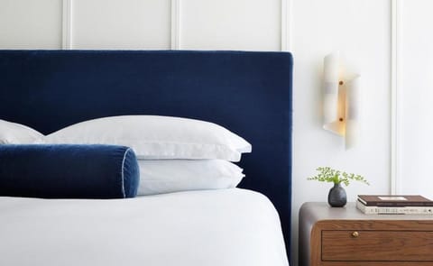 Sink into crisp linens against a bold, velvety headboard.