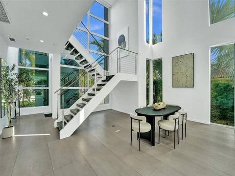 Refined open concept living space showcasing dramatic architectural stairway with contemporary furnishings and tropical views