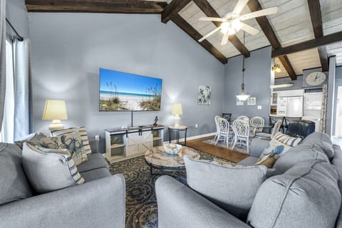 Spacious living room with vaulted ceilings, comfortable seating, and a large smart TV—ideal for movie nights and gathering with family and friends.