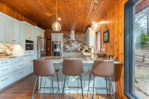 Kitchen with gas range, double oven, dishwasher, drip-style coffee maker, and breakfast bar seating for 3