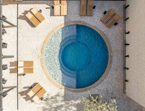 Dive into a sunlit pool oasis with serene seating.