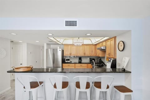 Bright and spacious kitchen featuring stainless steel appliances, granite countertops, and bar seating for easy conversations while cooking.