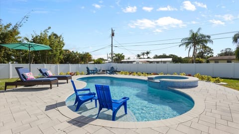 Relax in your private, fully fenced backyard with a heated pool, shallow sun shelf, sun loungers, in-water seating, and a sitting area with firepit at the edge of the pool deck.