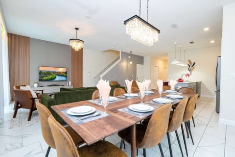 Open-concept living: crystal chandeliers, warm wood accents, and a chic kitchen flow around the 8-seat dining table-perfect for gathering after the parks.