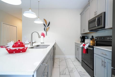 Chef-ready kitchen with quartz countertops, gray shaker cabinets, and stainless appliances. Pendant lighting and a spacious island with sink make meal prep a breeze.