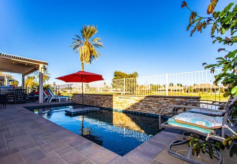 A patio with pergola and lounge chairs by the pool