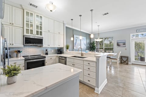 This stunning kitchen features quartz countertops, stainless steel appliances, and elegant pendant lighting for a modern coastal feel.