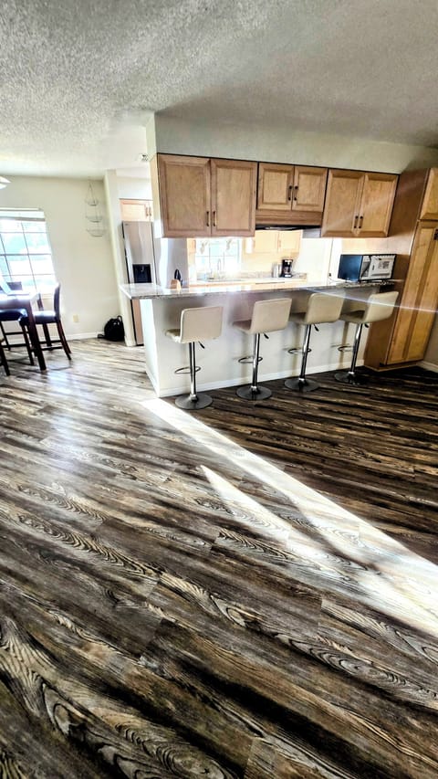 View from living room into kitchen, 4 bar stools along bar