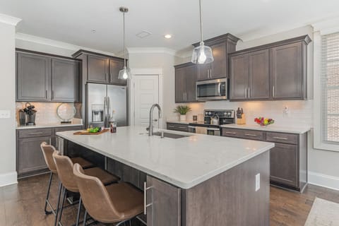 Unit 1: Fully equipped kitchen stocked with all culinary essentials, stainless steel appliances, and an island offering bar seating for 3 guests.