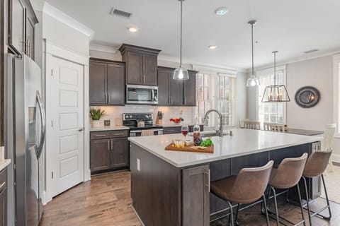 Unit 1: Fully equipped kitchen stocked with all culinary essentials, stainless steel appliances, and an island offering bar seating for 3 guests.