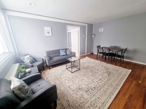 The living room comes furnished with essential pieces, including a comfortable sofa, a coffee table, TV stand, and dining table, providing immediate comfort upon move-in.
