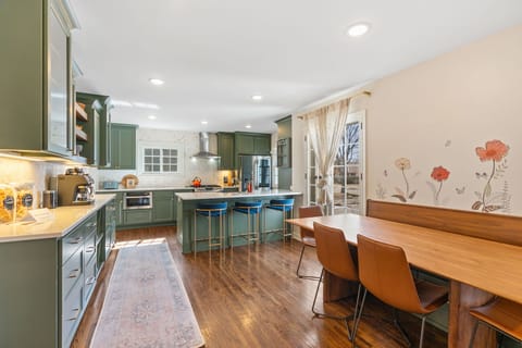 Your gourmet kitchen invites culinary adventures with forest-green cabinets, marble counters, and a spacious island perfect for morning coffee or evening conversations.