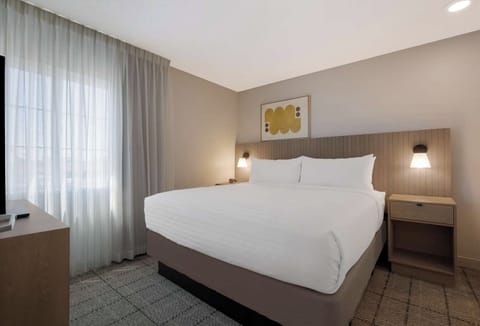Unwind in crisp linens beside soft, light-filled curtains.