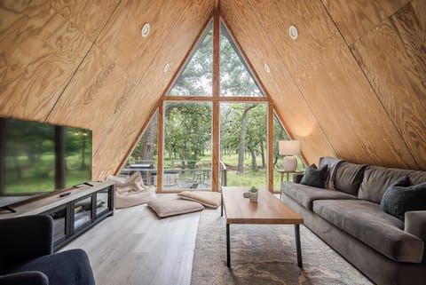 Soak in serene, hill country views through the floor-to-ceiling windows in the living room - complete with a smart TV and soft, oversized sofa.