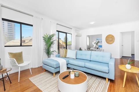 Unwind in a bright and airy living room with a comfortable light blue sofa, a stylish round coffee table, and warm wood floors.