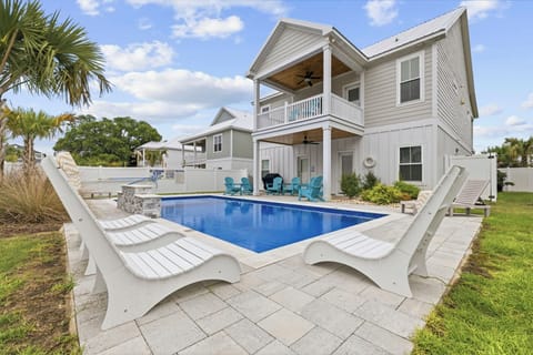 A private backyard pool with seating set beside the home and lounging by the pool,