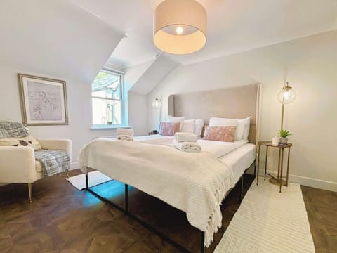 This bedroom feels fresh and serene, with twin beds, soft neutral tones, and cozy layered pillows. Warm lighting and a minimalist open wardrobe complete the boutique-style look.