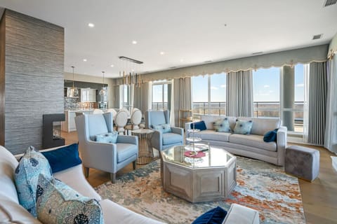 Living room with a Smart TV, 10 foot tall floor-to-ceiling windows, stunning electric fireplace and cozy seating options.