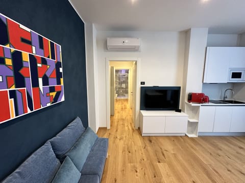 Living room with kitchenette, closet with fold-out bed, and TV with SKY