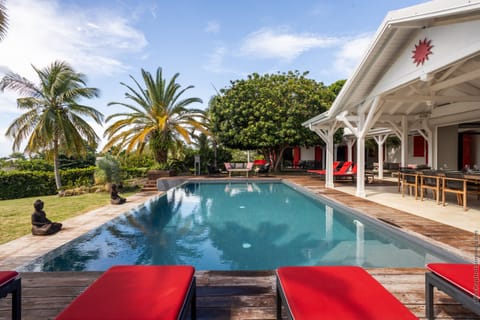 Sparkling swimming pool in the heart of a lush tropical garden with comfortable sun loungers.