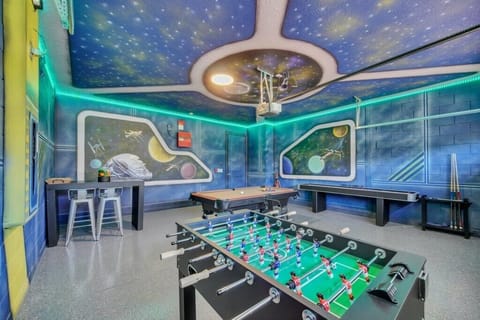 Futuristic games room with a pool table, foosball, and space-themed murals, ideal for family fun and entertainment.