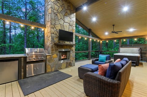 Generous back porch featuring cozy seating, a built-in grill, mini fridge, and inviting fireplace