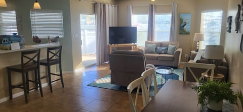 Open-concept living area filled with natural light, featuring comfortable seating, coastal décor. an