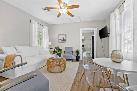 A bright and welcoming living area with natural light flooding through large windows. The space features cozy seating and a modern dining area perfect for gatherings.