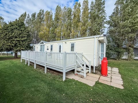 Cozy mobile home with spacious deck and lush greenery